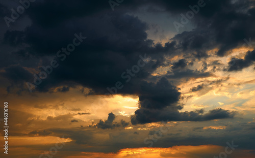beautiful sunset sky, bright sun and dark silhouette of clouds as a background