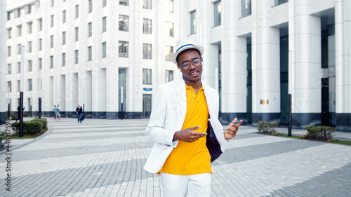 Joyful black man in glasses and white wireless headphones listens to music and dances