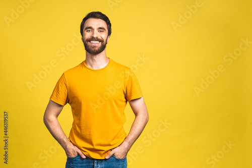 Happy young man. Portrait of handsome young bearded man in casual smiling while isolated over yellow background.