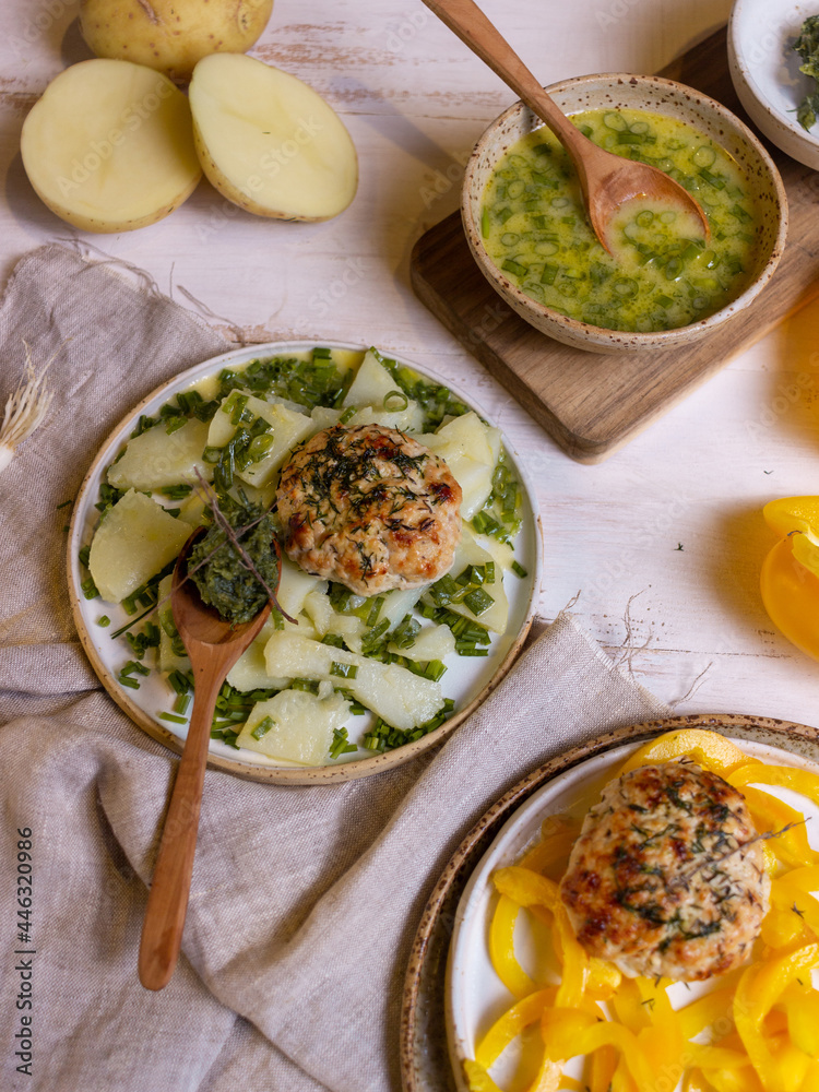 French-style potato salad and chicken cutlets on a light wooden table French-style potato salad and chicken cutlets on a light wooden table
