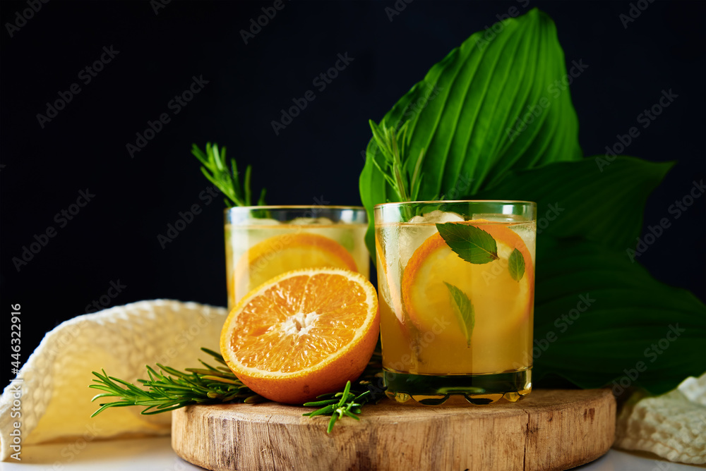 Lemonade with orange, rosemary and mint in glass on table. Summer fresh drink on dark background Lemonade with orange, rosemary and mint in glass on table. Summer fresh drink on dark background