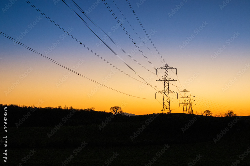 A winter sunset behind electricity power lines and pylons at Milton near Brampton, Cumbria UK