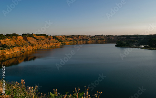 A beautiful lake in a deep abandoned quarry. Summer time, evening sunset. Scenery.
