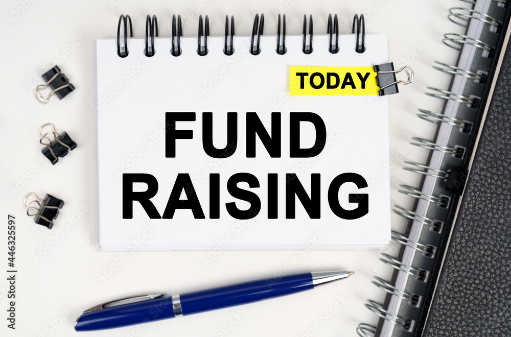 On the table is a pen and a notebook with inscriptions - Today and FUND RAISING On the table is a pen and a notebook with inscriptions - Today and FUND RAISING