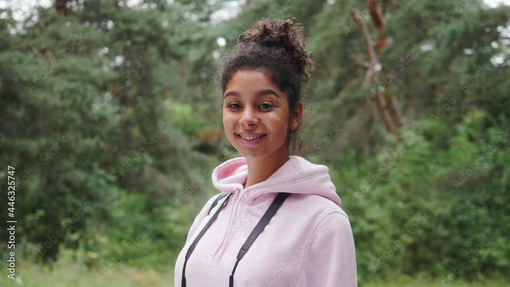 Portrait of a happy black african american woman smiling, tourist student, black fashion model smiling, curly afro hairstyle, generation z lifestyle, teenager walking, posing in forest Portrait of a happy black african american woman smiling, tourist student, black fashion model smiling, curly afro hairstyle, generation z lifestyle, teenager walking, posing in forest