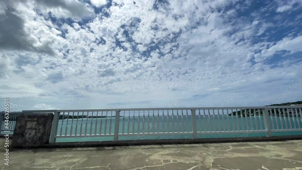 OKINAWA, JAPAN - JUNE 2021 : Driving at Kouri Island bridge. Wide camera point of view (POV), seaside road driving shot. Blue sunny summer sky. OKINAWA, JAPAN - JUNE 2021 : Driving at Kouri Island bridge. Wide camera point of view (POV), seaside road driving shot. Blue sunny summer sky.