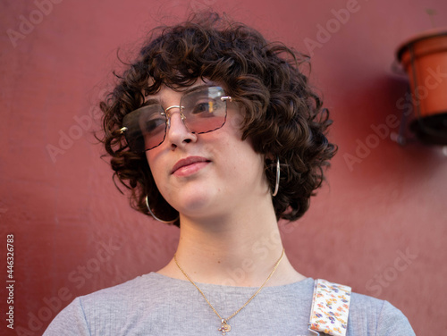 Retrato de joven con el pelo rizado y gafas de sol grandes en distintas aptitudes.
