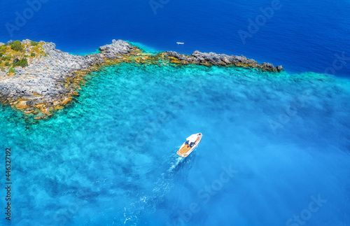 Speed boat on blue sea at sunny day in summer. Aerial view of motorboat on sea bay, rocks in clear azure water. Tropical landscape with yacht, stones. Top view from drone. Travel in Oludeniz, Turkey © den-belitsky