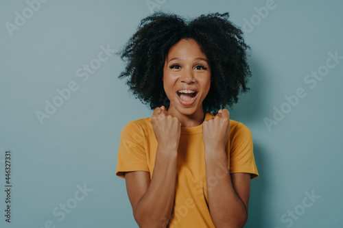 Εκτύπωση καμβά Happy dark skinned woman enjoys wonderful life, clenches fists with joy and scre