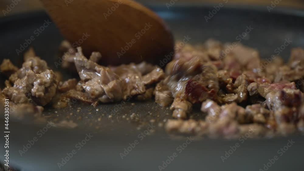 Stirring small pieces of beef searing and sizzling in a hot pan and oil on the stove - isolated close close up slow Stirring small pieces of beef searing and sizzling in a hot pan and oil on the stove - isolated close close up slow