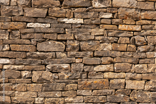 Rustic stone wall texture. Irregular stone wall in natural colors, brown, ocher. Textured background