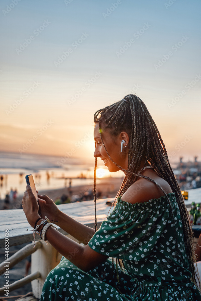 Joyful woman on beach with earphones and phone