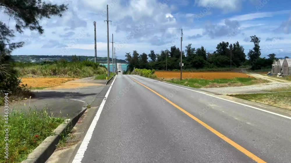 OKINAWA, JAPAN - JUNE 2021 : Driving at Kouri Island bridge. Wide camera point of view (POV), seaside road driving shot. Blue sunny summer sky. OKINAWA, JAPAN - JUNE 2021 : Driving at Kouri Island bridge. Wide camera point of view (POV), seaside road driving shot. Blue sunny summer sky.