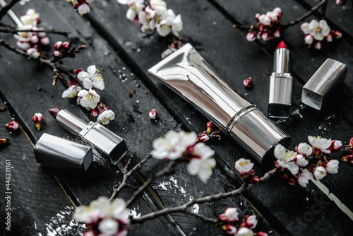 Set of blank silver cosmetic tubes on spring flowers background. SPA and makeup cosmetic products composition. Copyspace, close up, selective focus