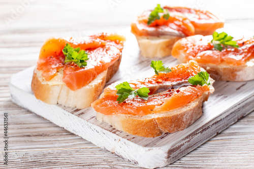 Slice of bread with smoked salmon and butter on wooden background. Grain yeast-free bread butter, parsley and fish on a wooden board.