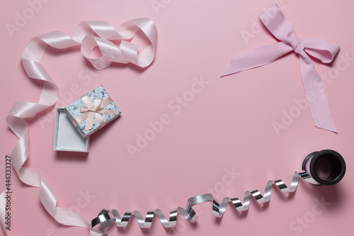 Small gift box with bow, pink and silver ribbon for gift wrapping on pink background