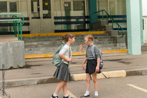 two cute happy girls schoolgirls with backpacks are playing near the school. High quality photo © Наталия Бражник