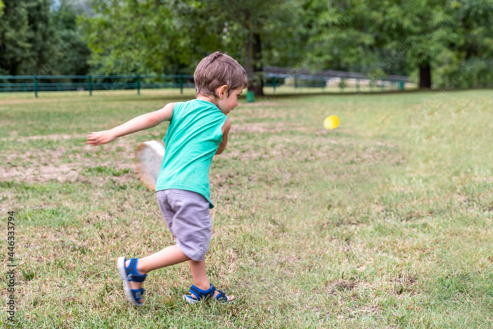 Fototapeta premium smiling cute child playing with an old tennis racket in a public park