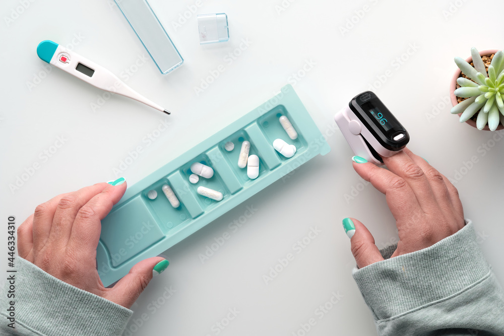 Patient hands with pills and pulse oximeter, finger digital device to