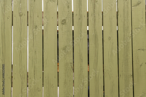 A wooden fence evenly painted light green / olive. Verticle boards. Banner space.	 photo