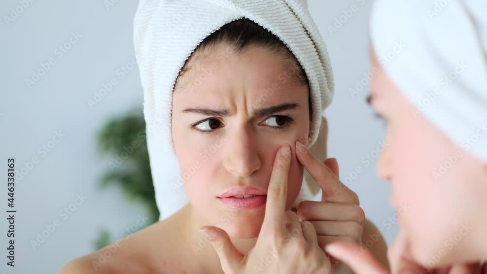 Video of beautiful young woman removing pimple from her face while looking at the mirror in a bathroom home. Video of beautiful young woman removing pimple from her face while looking at the mirror in a bathroom home.