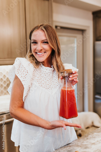 Smiling woman shows off her freshly made carafe of homemade juce photo