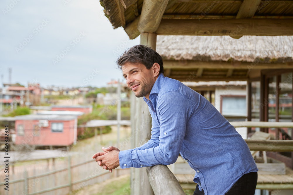 Young man in a light blue shirt leaning on the balcony Young man in a light blue shirt leaning on the balcony