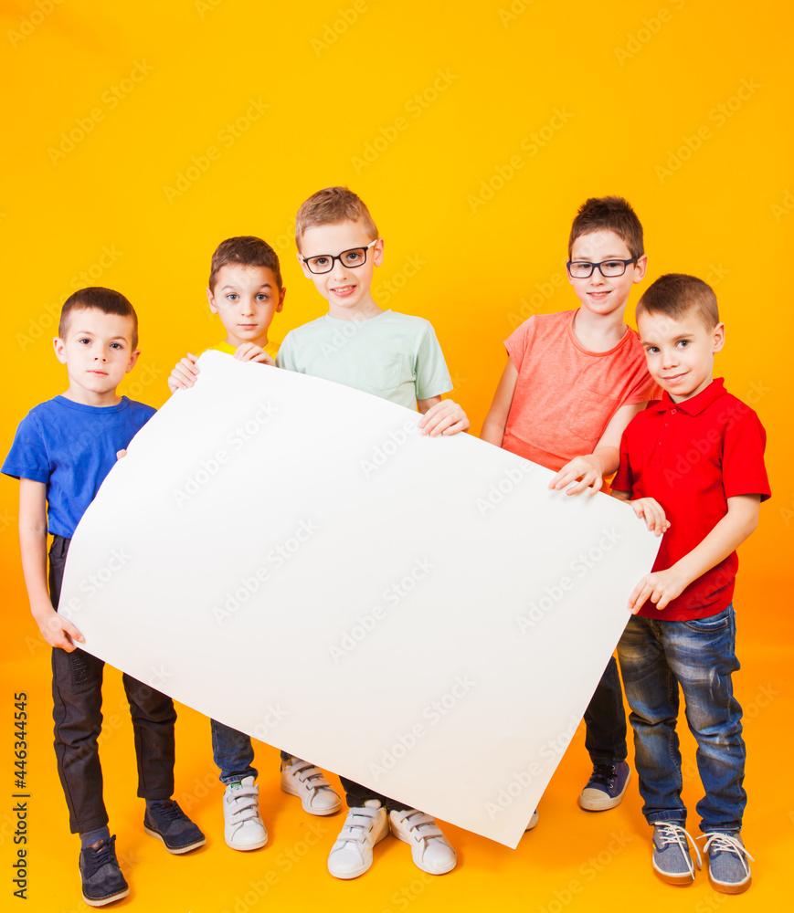 The happy different boys are holding a large white paper The happy different boys are holding a large white paper