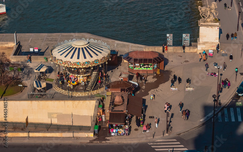 People walking near a caroussel next to a river photo