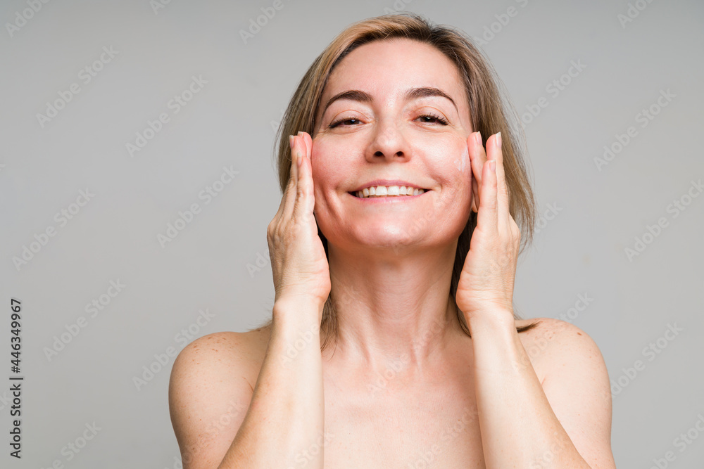 Happy older woman applying skincare products