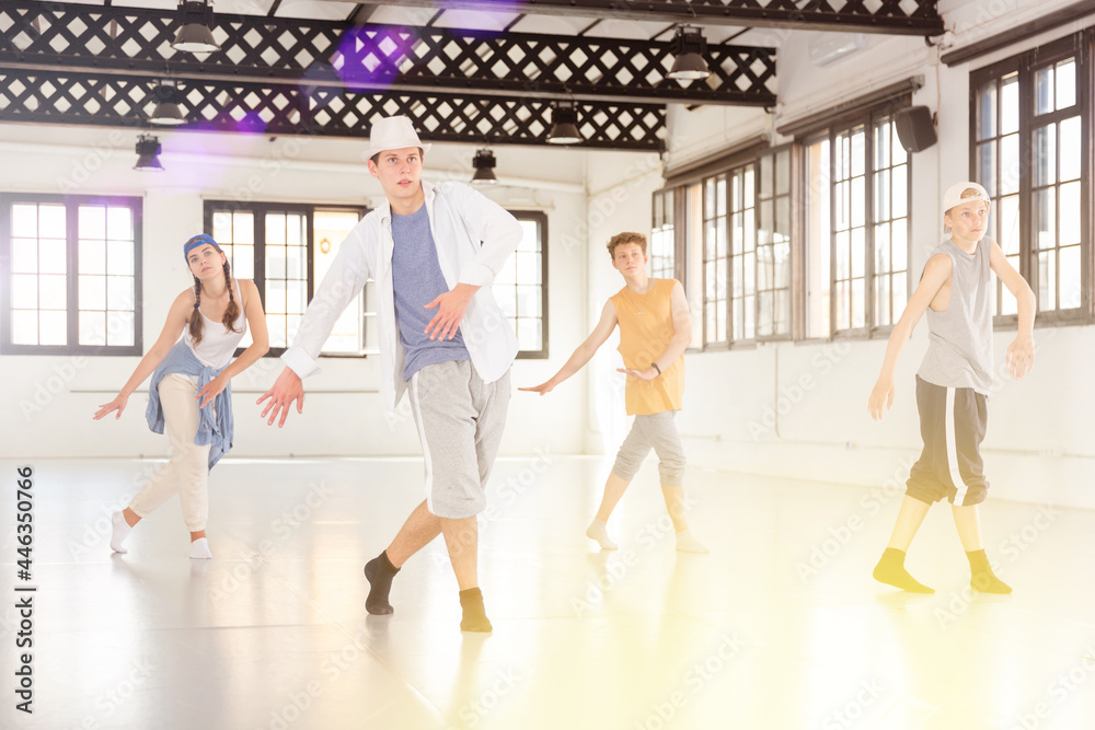 Group of teenagers practicing active dance movements at dance class