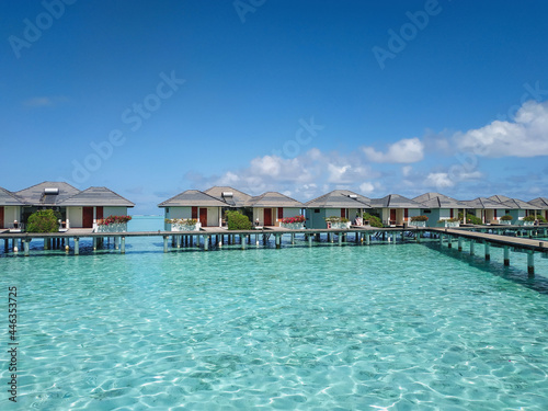 Villas on stilts (bungalows) surrounded by beautiful clear turquoise water of Indian Ocean. Resort summer vacation concept.