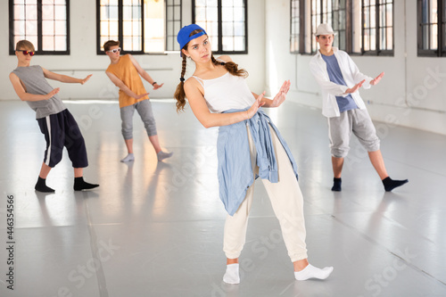 Group of teenagers training at dance class, practicing hip hop moves