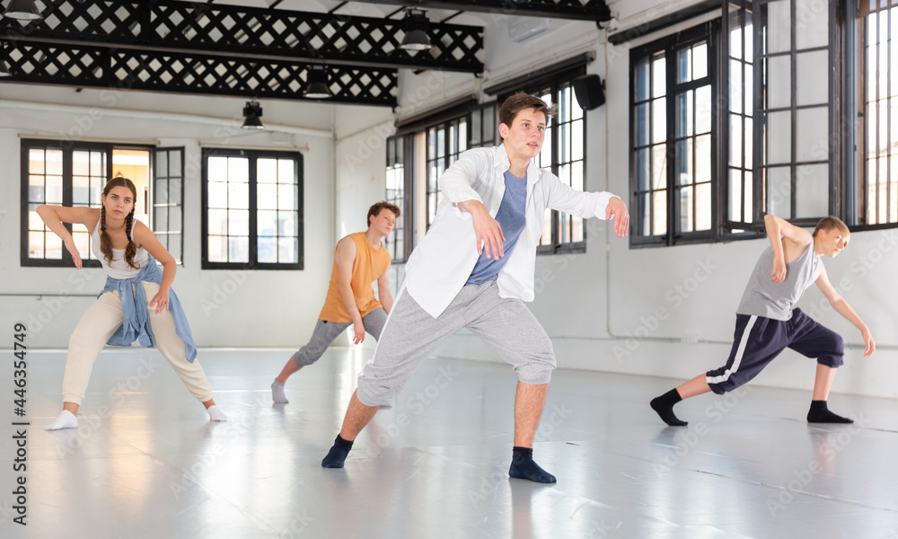 Teenage girl and boys having dance training in studio, performing contemporary dance elements