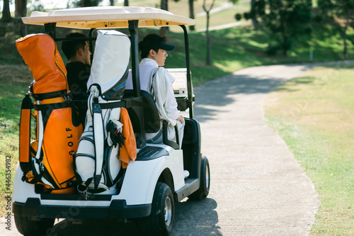 A golfer drives a golf cart down a golf course road while playing a game. photo