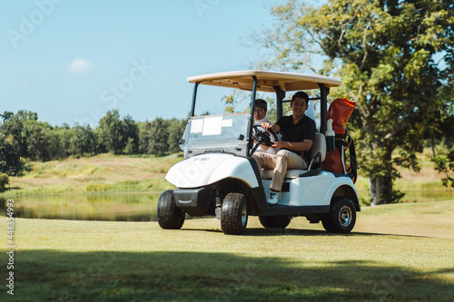 Golfers happily driving Golf carts on the green lawn.