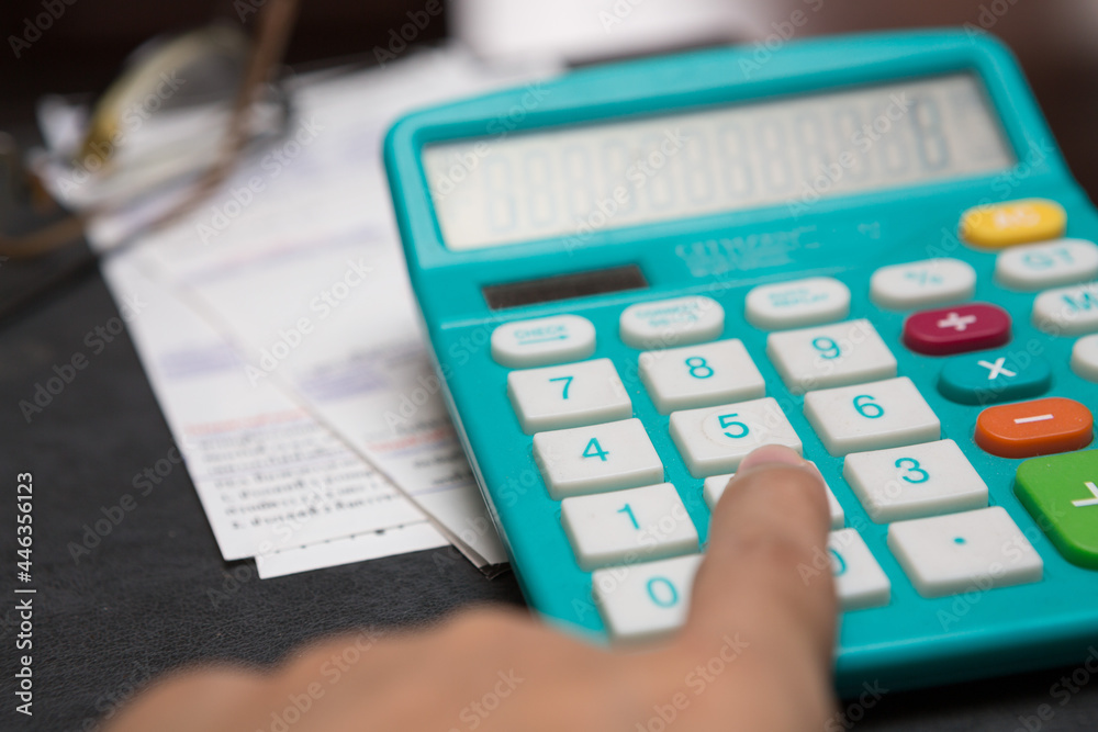 Fingers pressing the calculator on the expense bill for the savings concept Fingers pressing the calculator on the expense bill for the savings concept