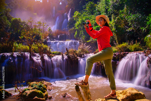 Tourists enjoying the beautiful view of a grand waterfall tumbling down the rocky cliff into