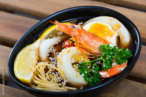 Dish of Asian cuisine spicy soup with squid, shrimp, egg noodles and sesame