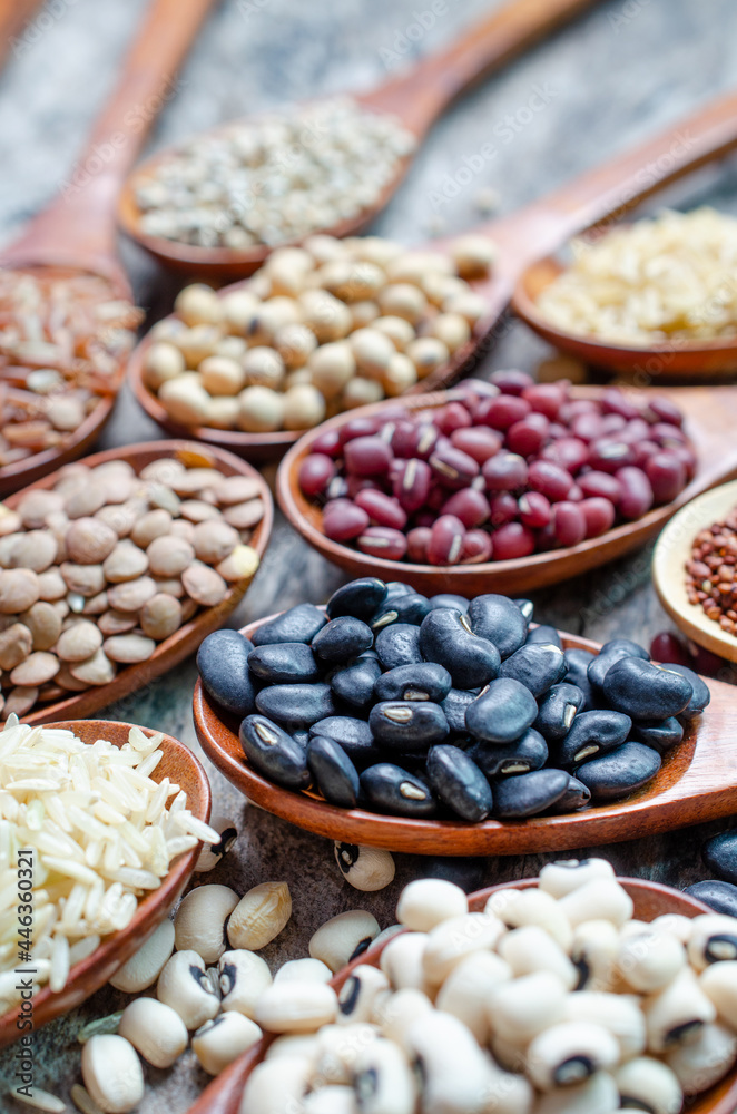 Closed up organic black bean seed with variety kinds of dry organic cereal and grain in wooden spoon on grunge background, for carbohydrate or clean food ingredient and agricultural product concept