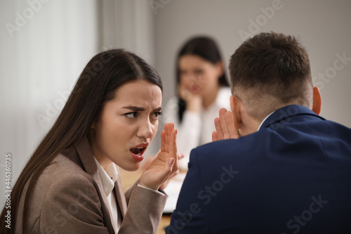 Coworkers bullying their colleague at workplace in office,