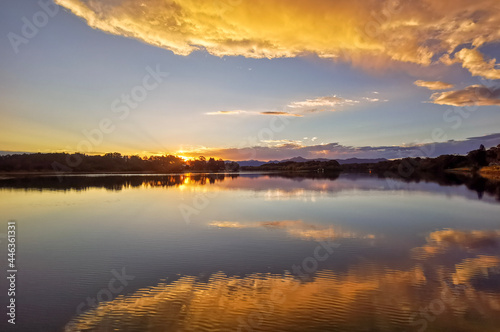 The last moment before sunset with a perfectly clear evening light over a calm coastal estuary in eastern Australia, making a perfect reflection of the overhead clouds glowing with the sunset light.