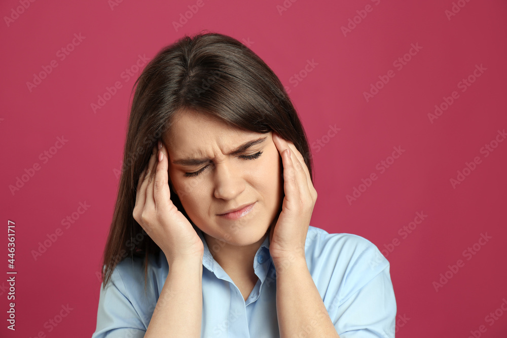 Young woman suffering from migraine on crimson background Young woman suffering from migraine on crimson background