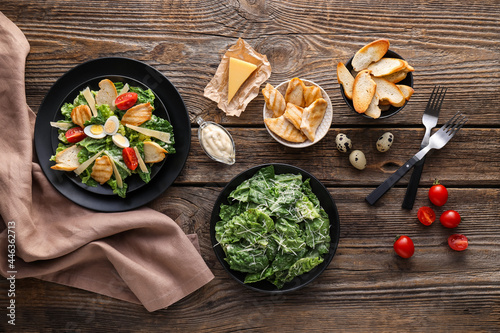 Composition with tasty Caesar salad and sauce on wooden background