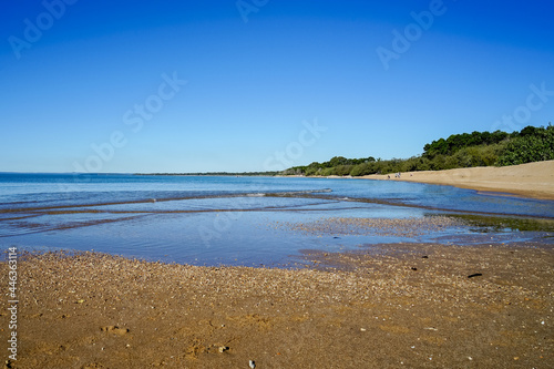 Gentle waves lap the sandy shore at low tide, at Hervey Bay, Queensland on a sunny afternoon 
