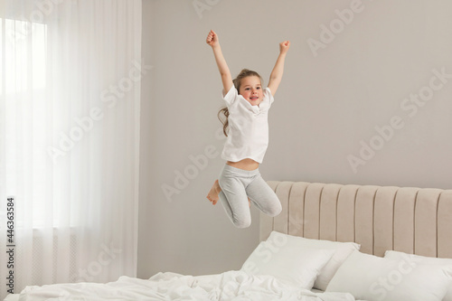 Fototapeta Naklejka Na Ścianę i Meble -  Cute little girl jumping on bed at home