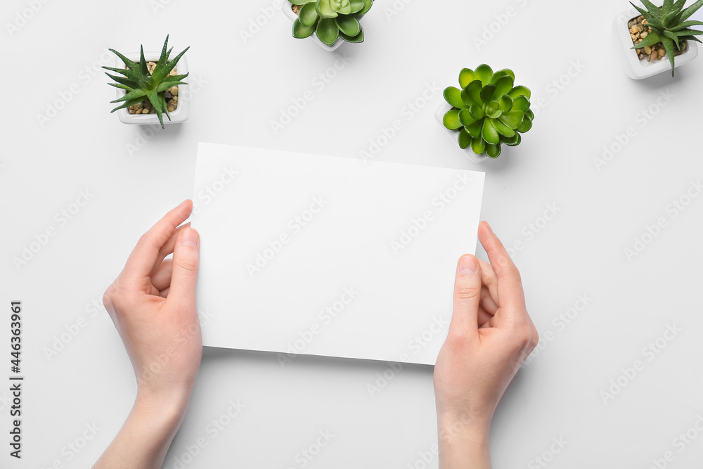 Female hands with blank sheet of paper and succulents on light background Female hands with blank sheet of paper and succulents on light background