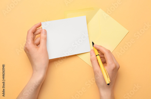 Female hands with blank sheet of paper, envelope and pen on color background
