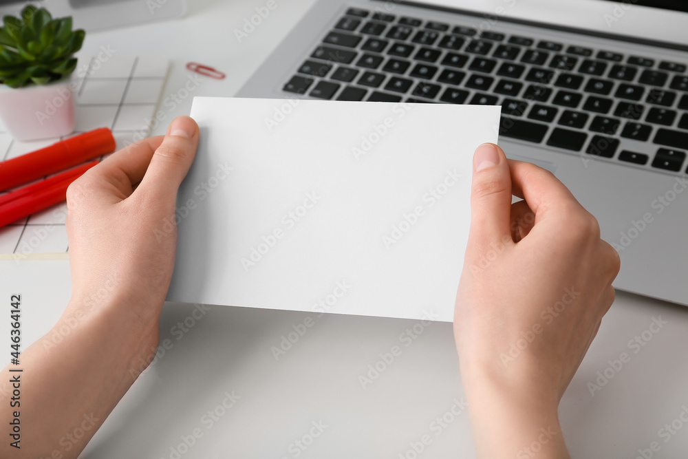 Female hands with blank sheet of paper and laptop on light background, closeup Female hands with blank sheet of paper and laptop on light background, closeup
