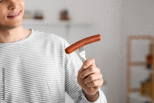 Young man with tasty sausag...